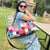 Woman holding a colorful checkered handbag in an outdoor setting